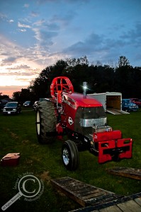 Tractor pulling red tractor at sunset