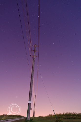 Telephone pole highlighted by full moon and urban light pollution